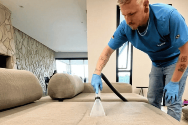 Profissional da Fritz Higienização realizando limpeza profissional de estofado com equipamento especializado